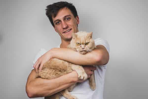 Čovek drži namrštenu mačku